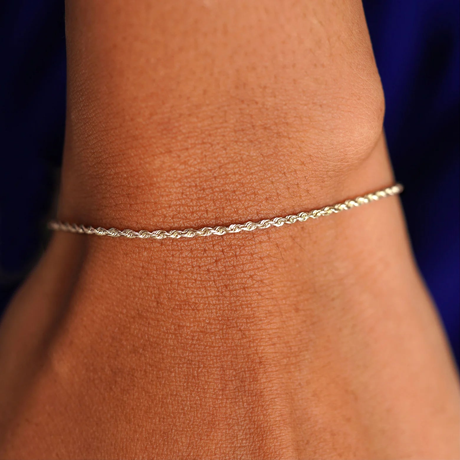 A model's wrist wearing a solid 14k champagne gold Rope Bracelet