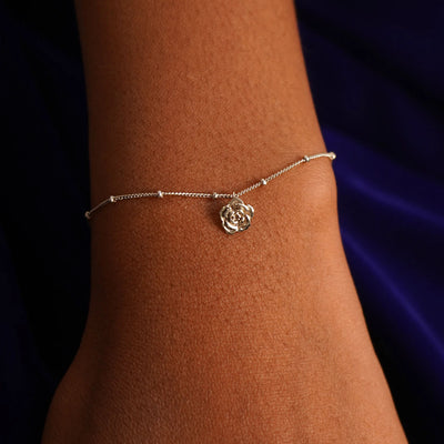 Close up view of a model's wrist wearing a champagne gold Rose Charm on a Beaded Essential Chain