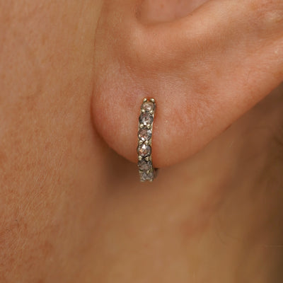 Close up view of a model's ear wearing a champagne gold Small Salt and Pepper Diamond Huggie Hoop