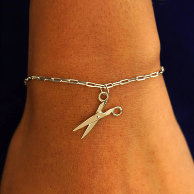 Close up view of a model's wrist wearing a champagne gold Scissors Charm on a Butch Chain Bracelet
