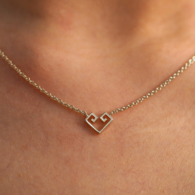 A close up view of a model's neck wearing a champagne gold Small Chere Heart Necklace