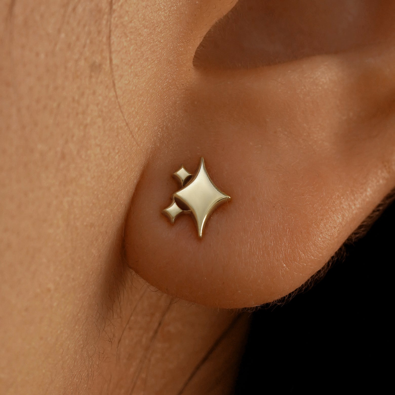 Close up view of a model's ear wearing a 14k champagne gold Sparkly Emoji Earring