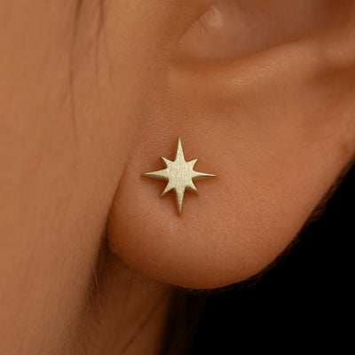Close up view of a model's ear wearing a 14k champagne gold Starburst Earring
