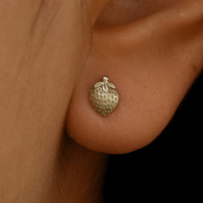 Close up view of a model's ear wearing a 14k champagne gold Strawberry Earring