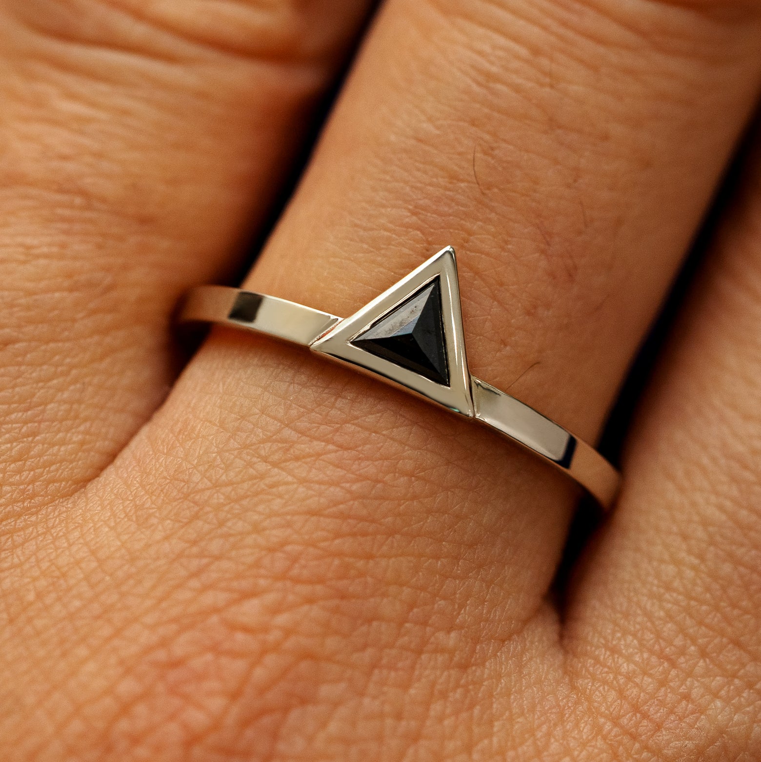 Close up view of a model's hand wearing a solid 14k champagne gold Triangle Diamond Ring