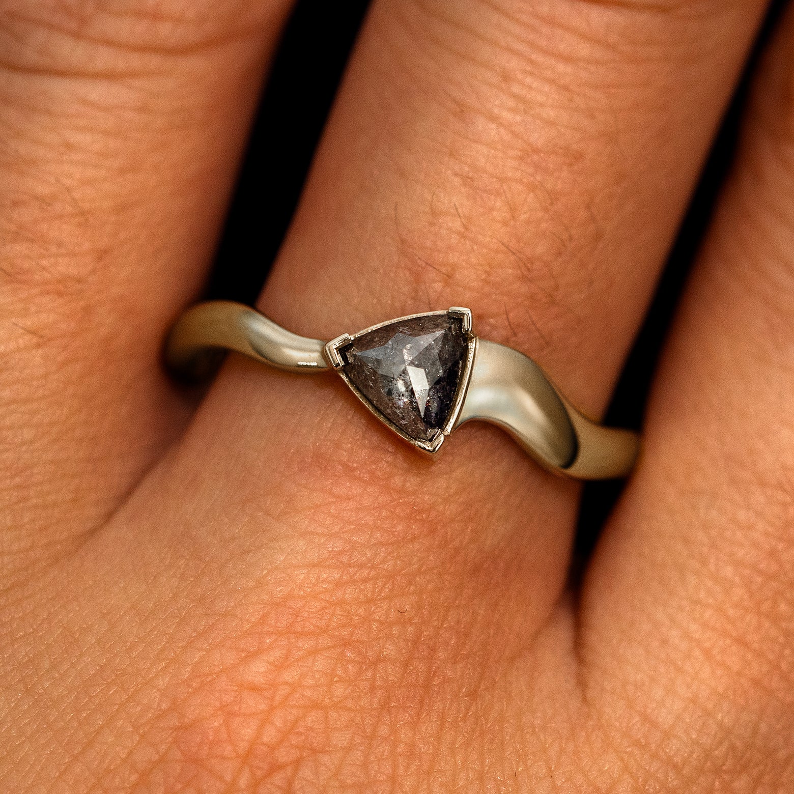 A model's hand wearing a 14k champagne gold Trillion Salt and Pepper Diamond Wavy Ring