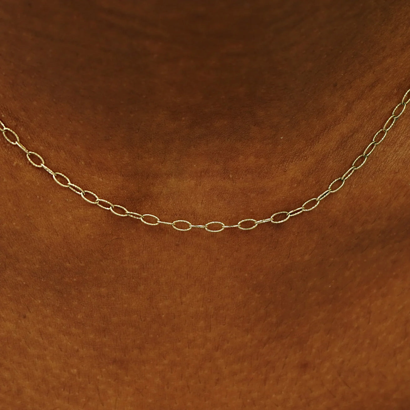 Close up view of a model's neck wearing a solid champagne gold Veren Chain