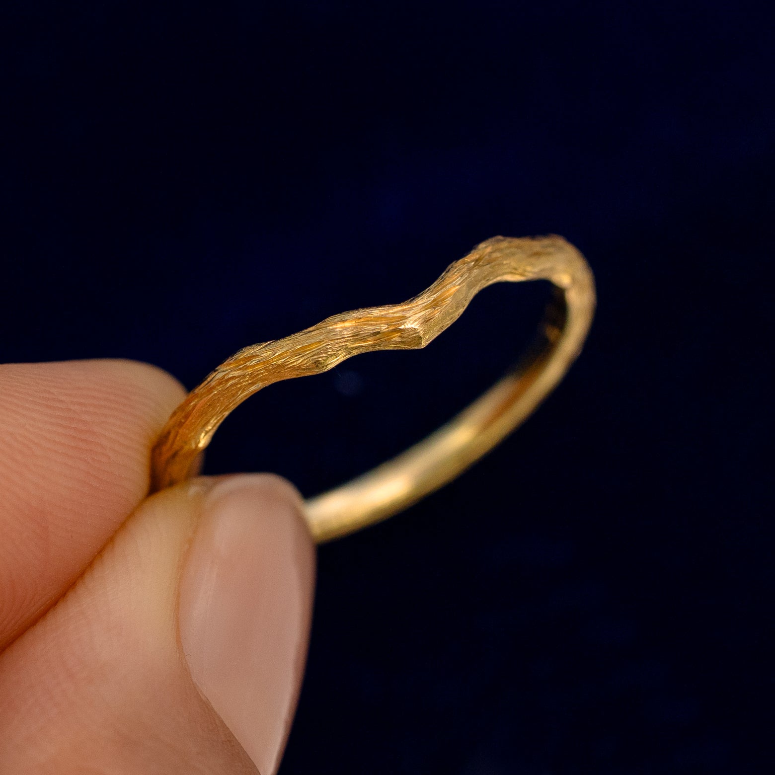 A model holding a Chevron Branches Band up to show the details of the chevron design and the inside of the ring