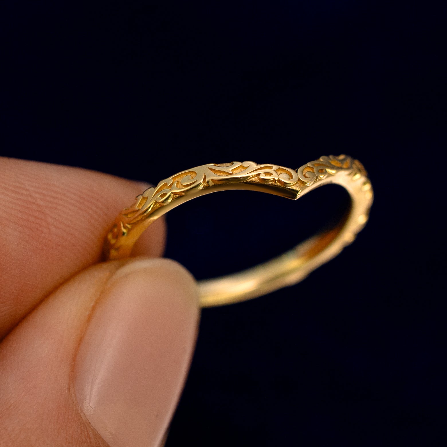 A model holding a Chevron Filigree Band up to show the details of the design and the inside of the ring