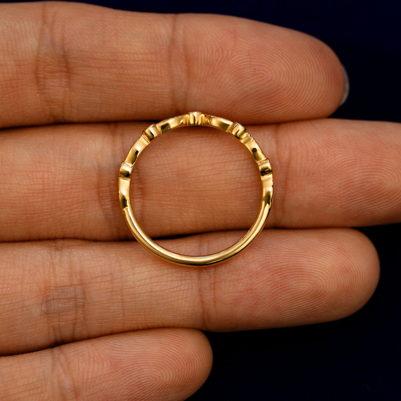 A Chevron Leaves and Round Diamonds Band lying flat in a models hand to show the thickness of the Ring