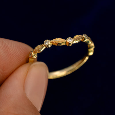 A model holding a Chevron Leaves and Round Diamonds Band up to show the details of the design and the inside of the ring