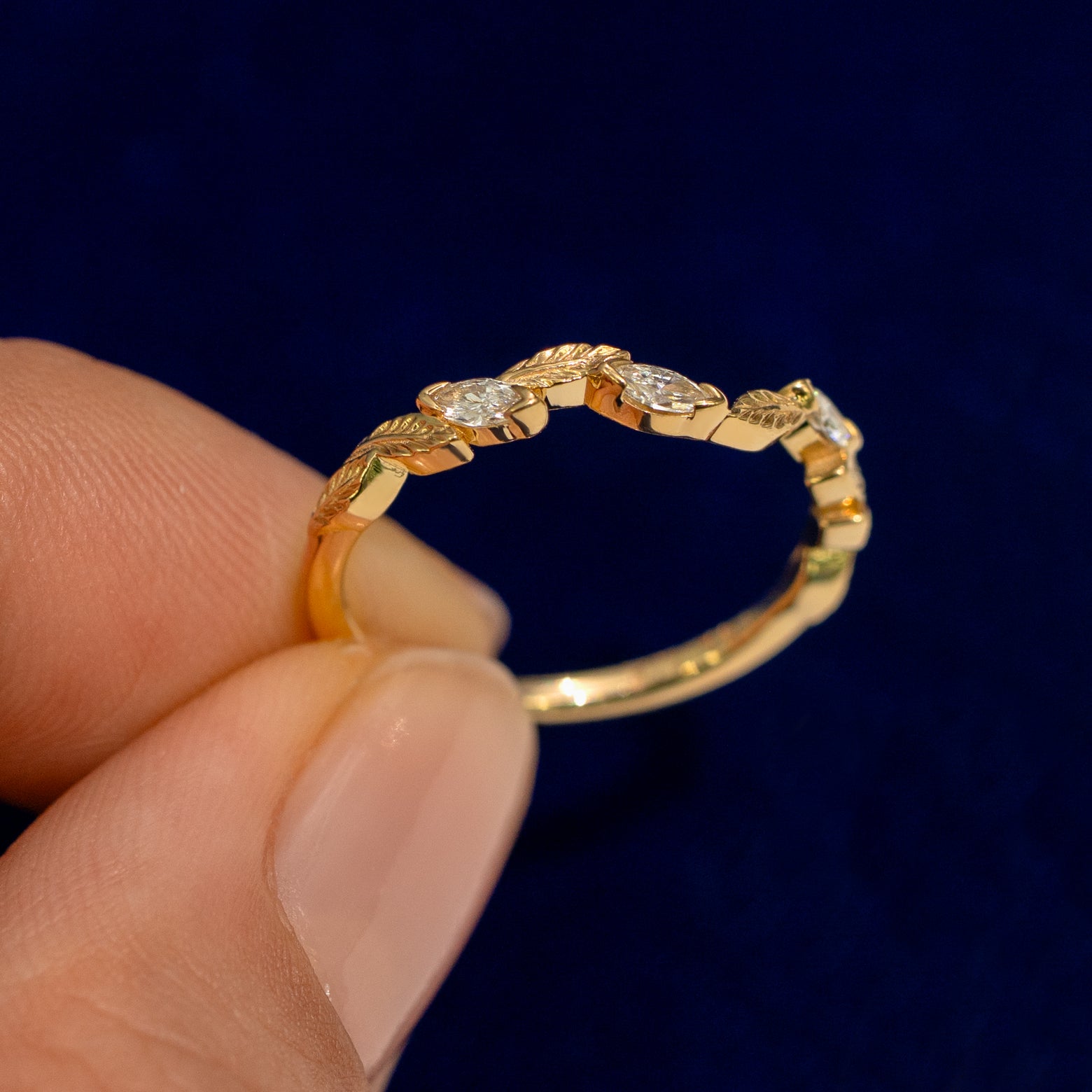 A model holding a Chevron Leaves and Marquise Diamonds Band up to show the details of the design and the inside of the ring