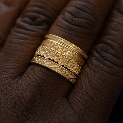 A model wearing four Chuvash inspired patterned wedding bands stacked on their middle finger