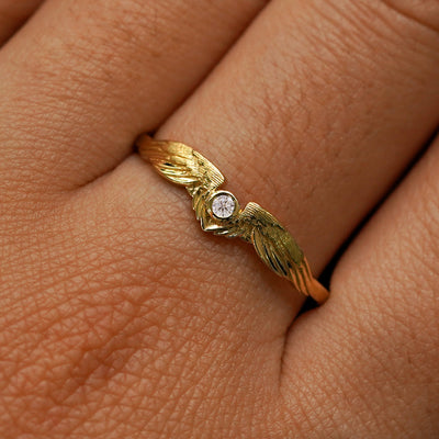 Close up view of a model's fingers wearing a 14k yellow gold Clear Diamond Wings Ring