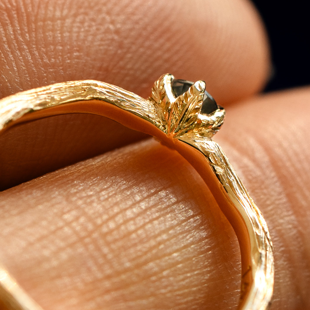 An angled view of a Montana Teal Sapphire Waved Branch Ring resting on a model's fingers to show underneath the setting