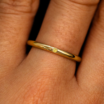 A 14k yellow gold Flush Set Round Yellow Diamond Ring on a model's finger