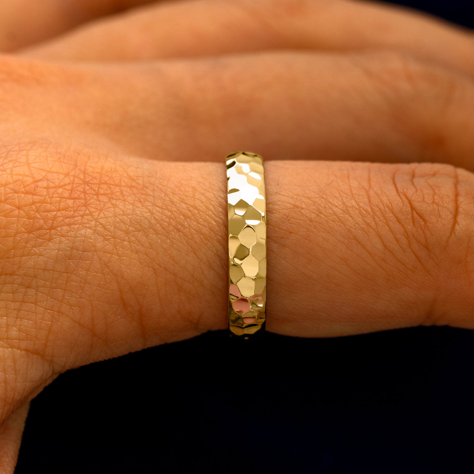 Side view of a Curvy Hammered Band on a model's finger
