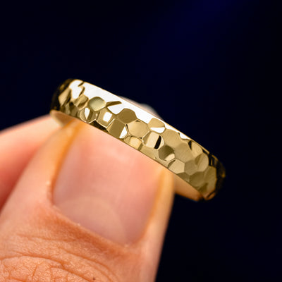 A model holding a Curvy Hammered Band tilted to show the side of the ring