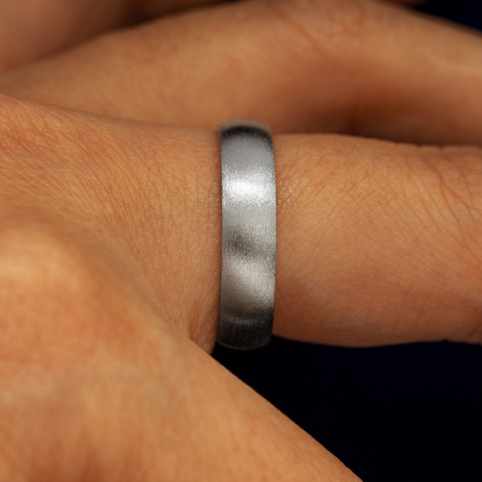 Side view of a Silver Curvy Matte Band on a model's finger
