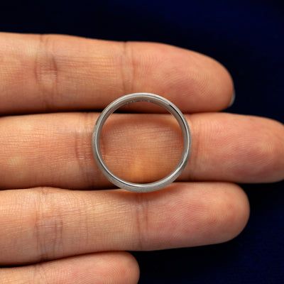A Silver Curvy Matte Band resting on a model's fingers to show the thickness of the band
