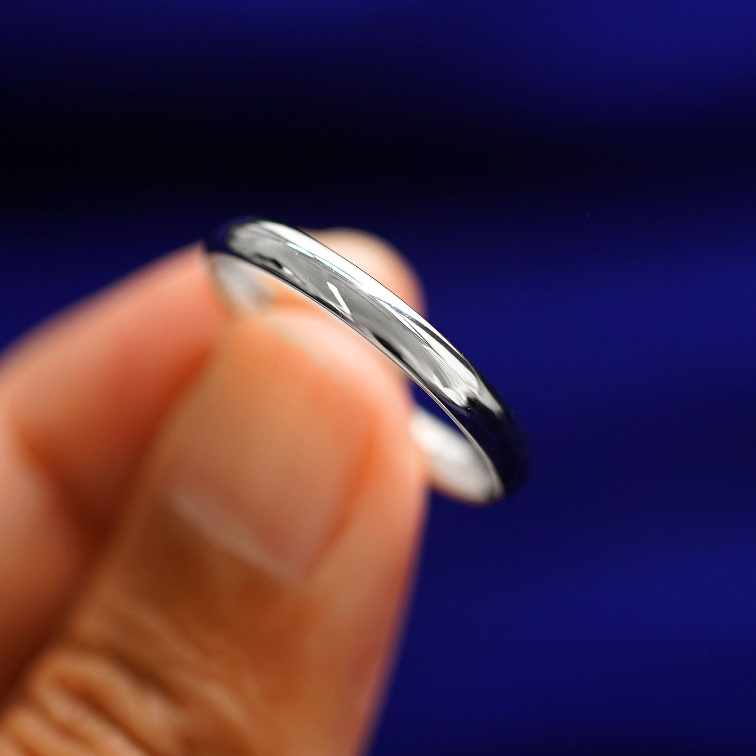 A model holding a Silver Curvy Mirror Band tilted to show the curve of the band