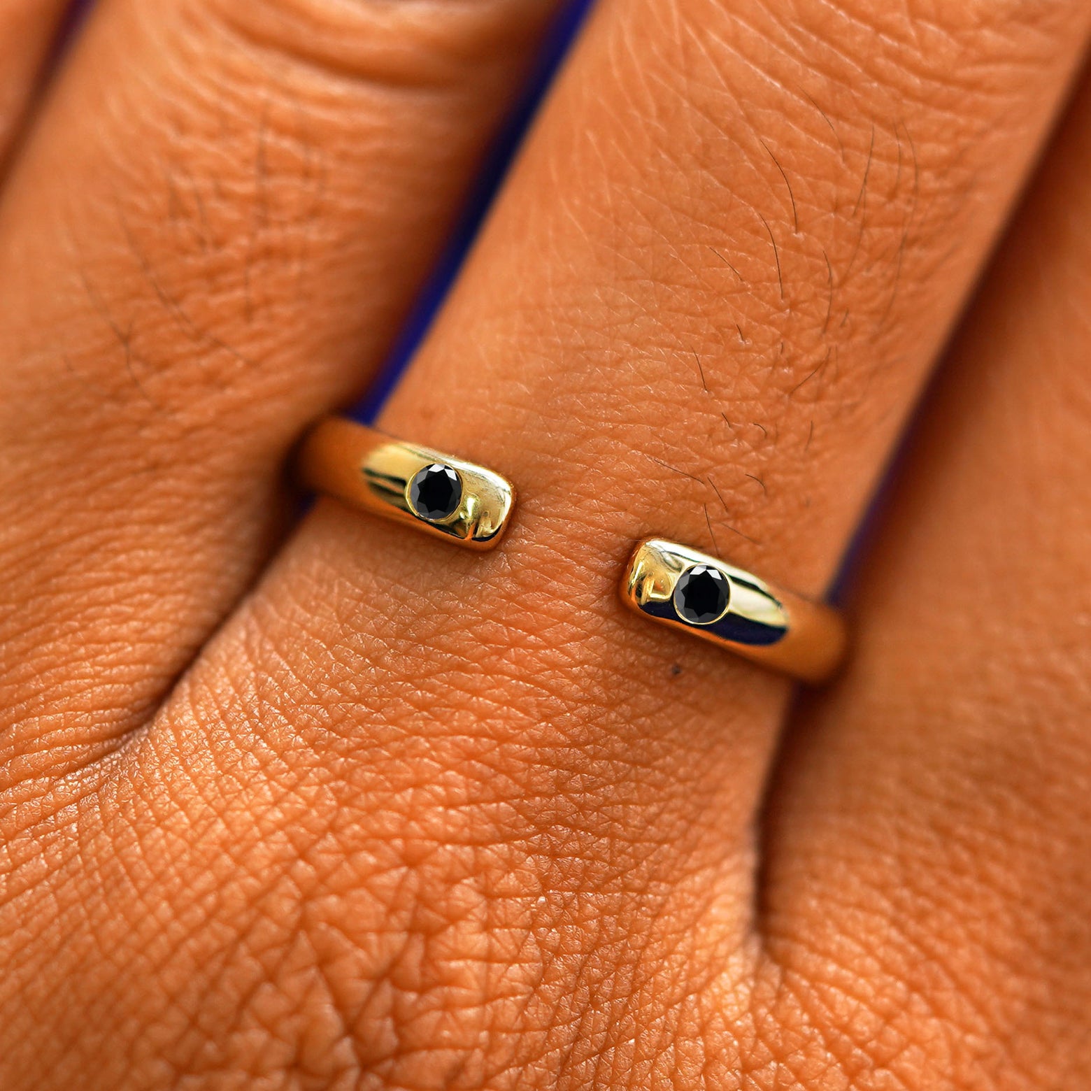 Close up view of a model's fingers wearing a 14k yellow gold Open Black Diamond Curvy Band