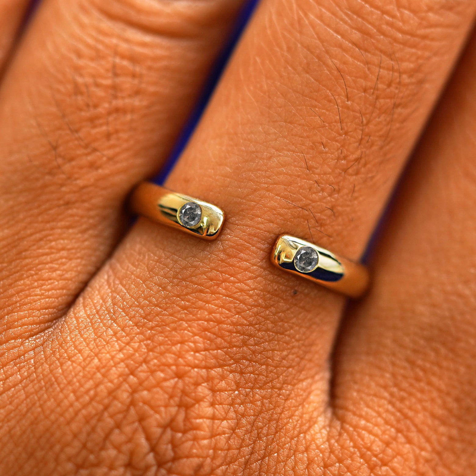 Close up view of a model's fingers wearing a 14k yellow gold Open Salt and Pepper Diamond Curvy Band