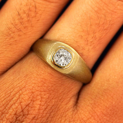 Close up view of a model's fingers wearing a 14k yellow gold Cushion Lab Clear Diamond Signet Ring