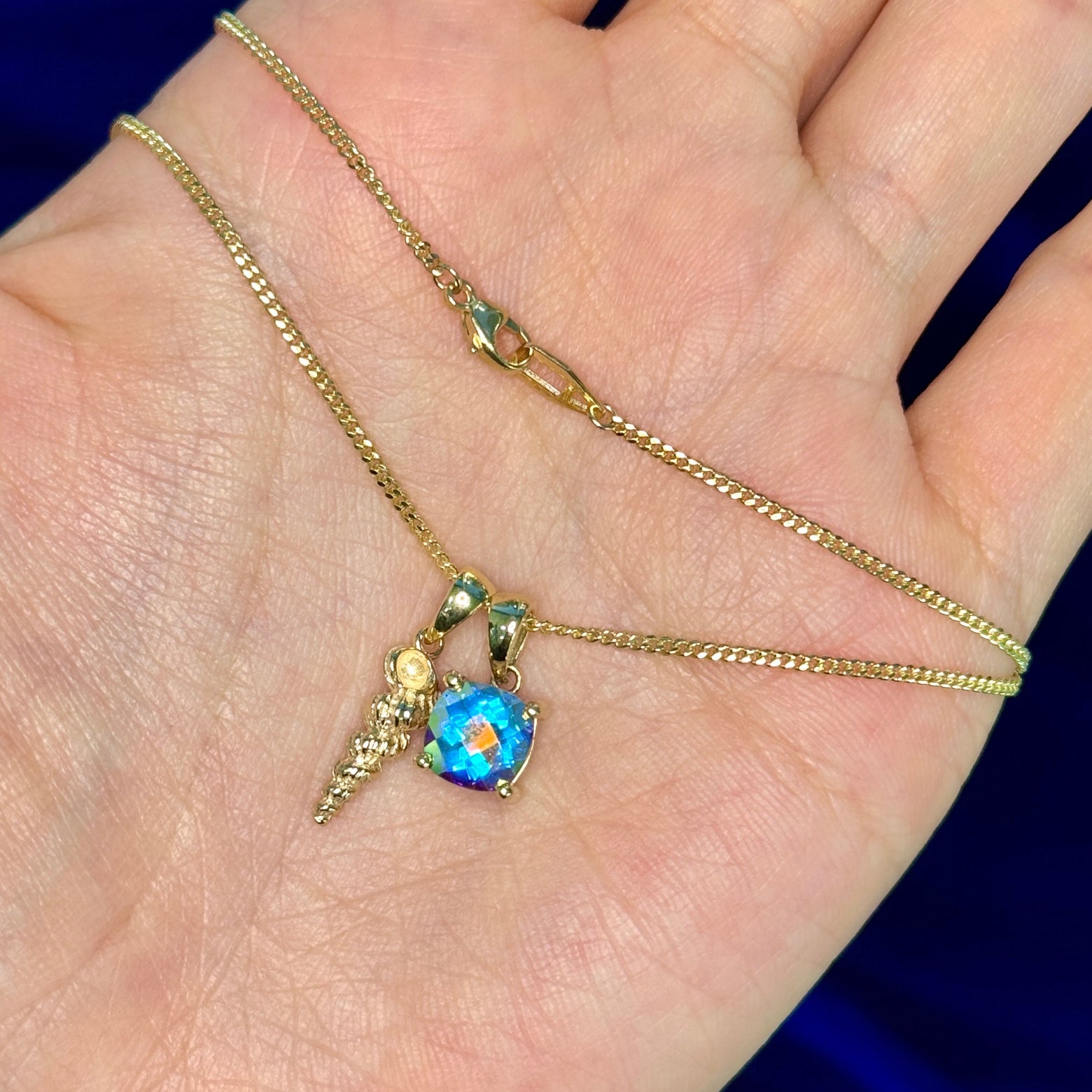A cushion mermaid topaz and seashell necklace on model's hand