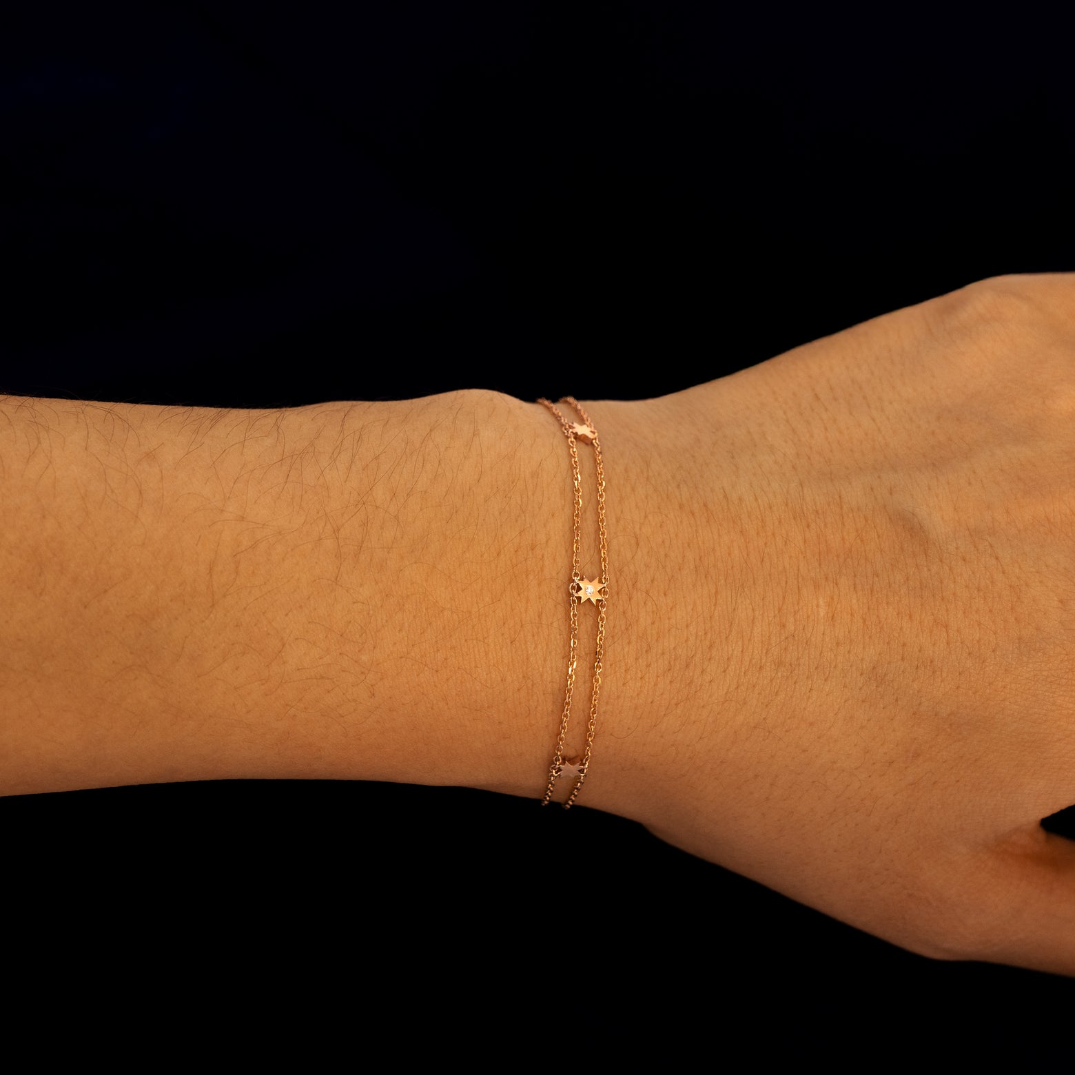 A model wearing a rose gold double chain 8 pointed star bracelet