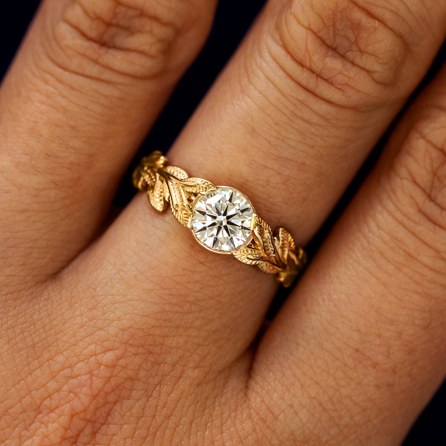 Close up view of a model's fingers wearing a 14k yellow gold Lab Clear Diamond Leaves Ring