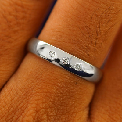 Close up view of a model's fingers wearing a 4mm Silver Curvy Mirror Band with three diamonds