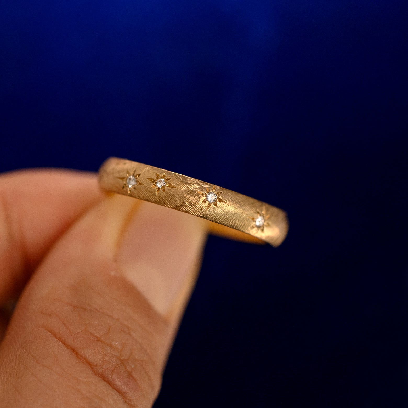 A model holding a Curvy Diamond Stars Velvet Band up to show the details of the design and the inside of the ring