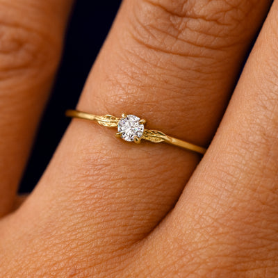 A solid 14k yellow gold Clear Diamond Two Leaf Ring on a model's finger