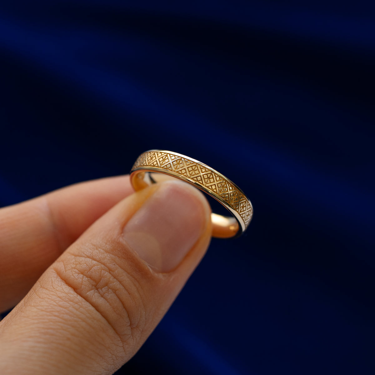 A model holding a diamond patterned band between two fingers to show engraved pattern details