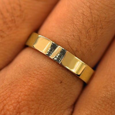 Close up view of a model's hand wearing a solid yellow gold Double Baguette Salt and Pepper Diamond Band