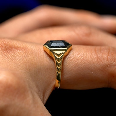 Side view of a model's finger wearing a solid 14k gold Chronos Ring to show the engravings