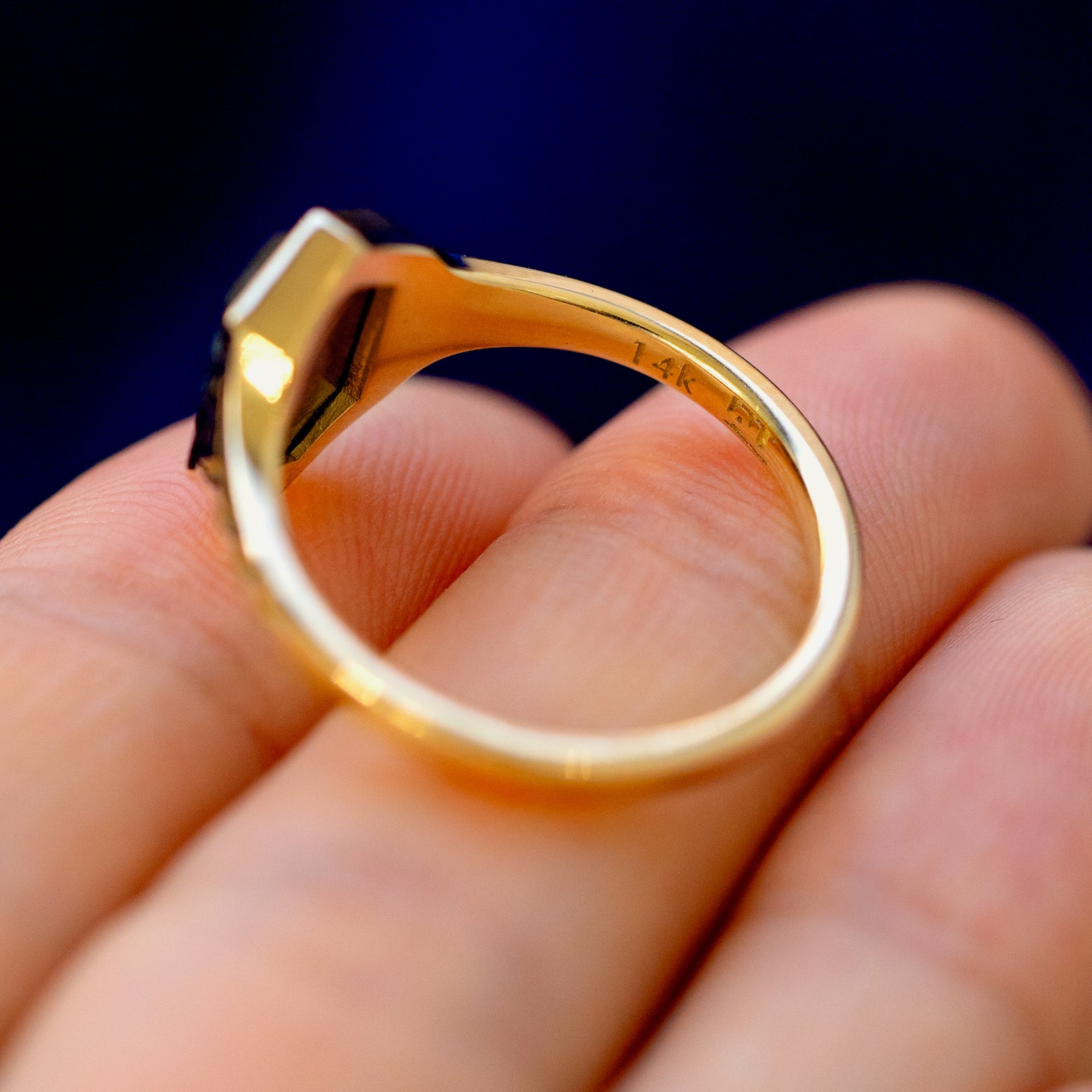 A 14 karat gold black diamond Chronos Ring lying on a model's fingers to show the stamp and underside of the stone