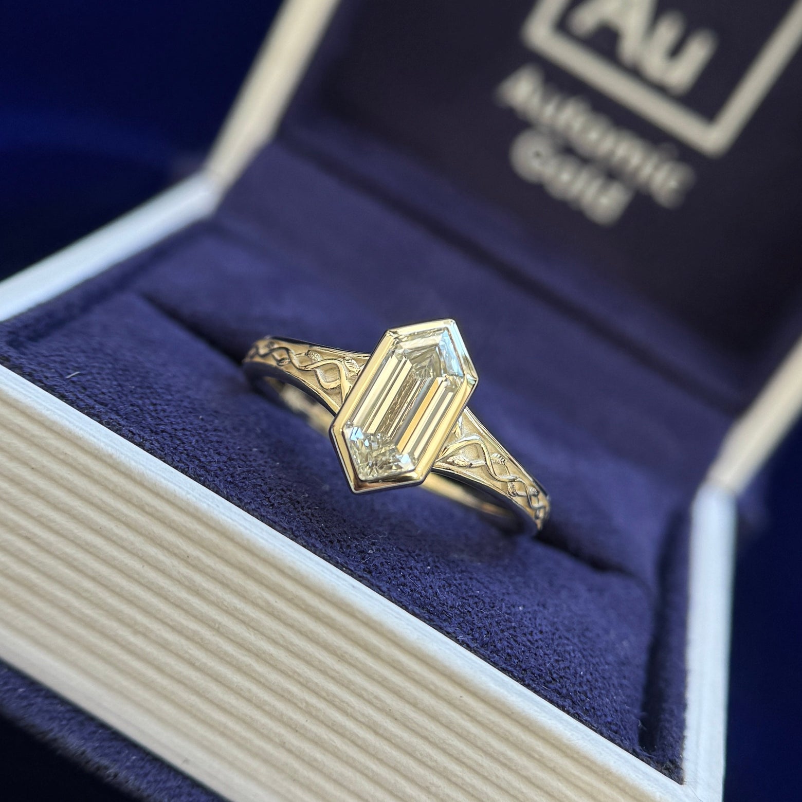 front view of 14k Champagne Gold and Bezel-set 1.4ct Elongated Hexagon Lab Diamond on Seraphine-style Celtic Engravings with Leaves Band Half-way Around the Band Custom Ring, Size 8