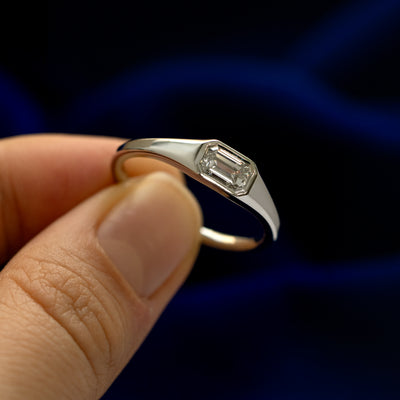 A model holding an Emerald Cut Lab Created Diamond Signet Ring tilted to show the side of the band