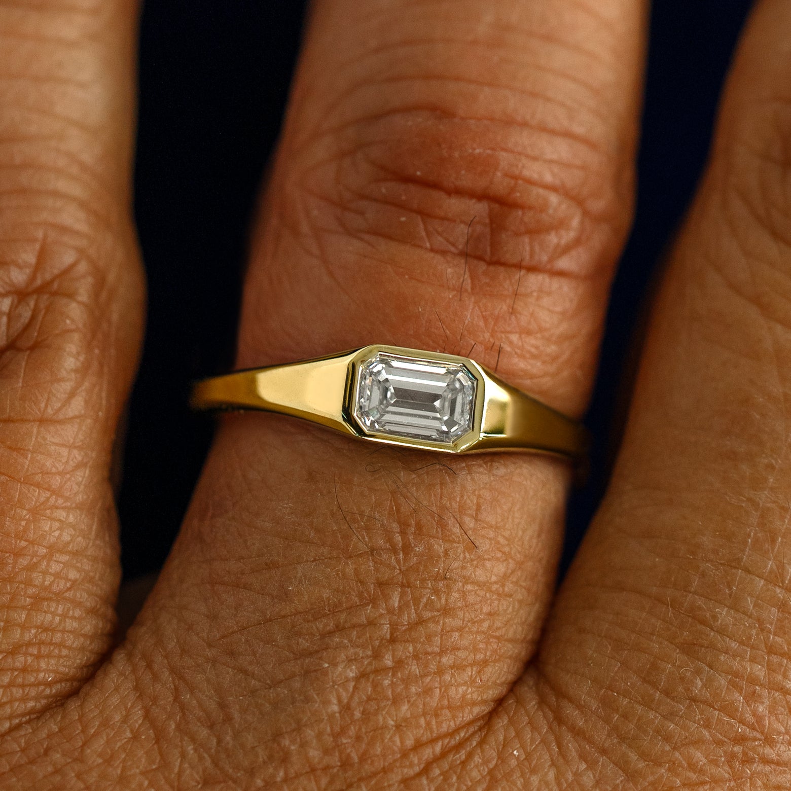 A model wearing a solid gold Emerald Cut Diamond Signet Ring