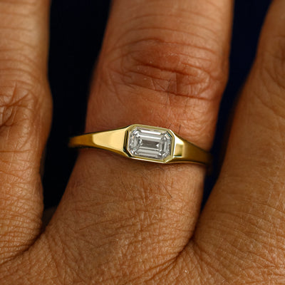 A model wearing a solid gold Emerald Cut Diamond Signet Ring