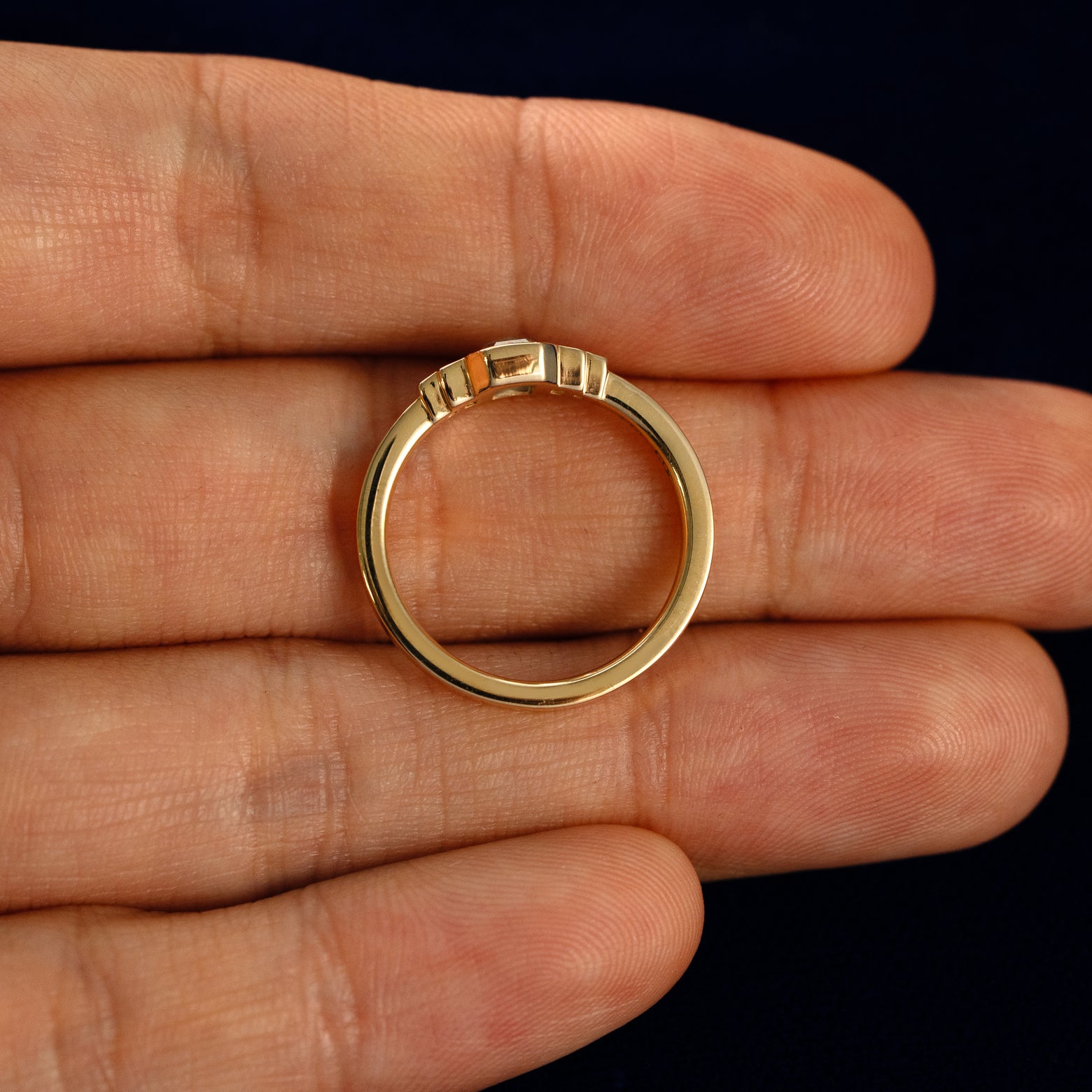 A yellow gold Emerald Cut Salt and Pepper and Clear Baguette Diamond Ring in a model's hand showing the thickness of the band