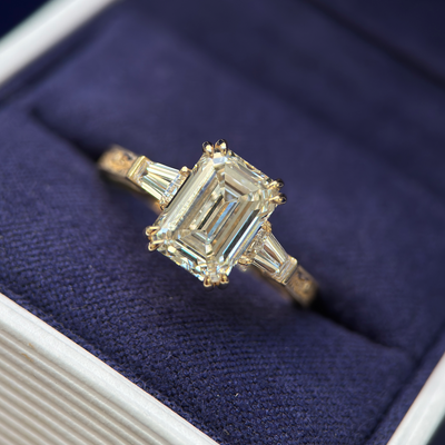 front view of 14k Yellow Gold and Prongs-set 3ct Emerald-cut Lab Diamond with 2pc Tapered Baguette Lab Diamonds on Vintage Filigree Flower Leaf Engraved Milgrain Band Custom Ring, Size 8