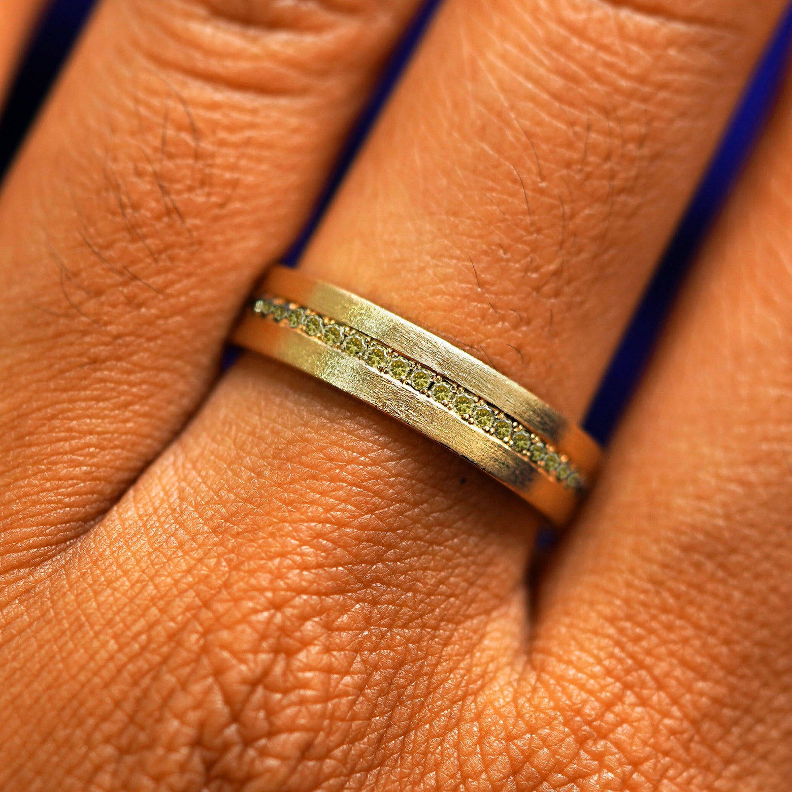 Close up view of a model's fingers wearing a 14k yellow gold Endless Champagne Diamond Band