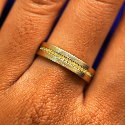 Close up view of a model's fingers wearing a 14k yellow gold Endless Yellow Diamond Band