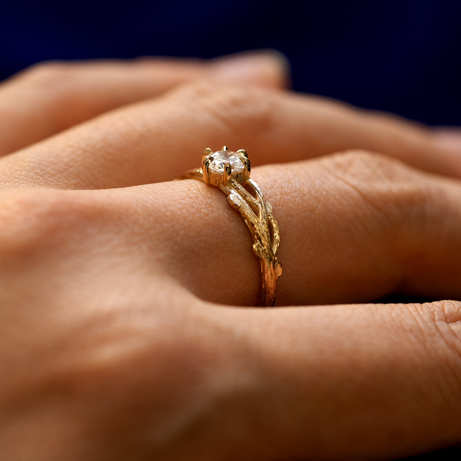 Side view of a Lab Diamond Branches Ring on a model's finger showing three braided tree branches going to the center stone