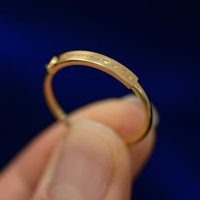 A model holding a bezel set gemstone bar ring tilted to show the thickness of the bar