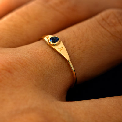 A model wearing a gemstone monogram ring to show the block font initials on the side on the gem