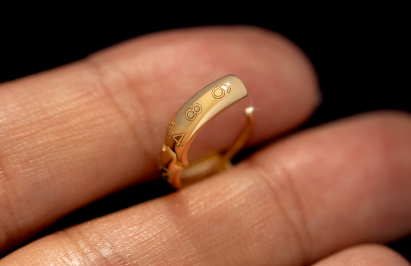 A solid yellow gold wide huggie hoop with the numbers 6 8 and 14 engraved on the front